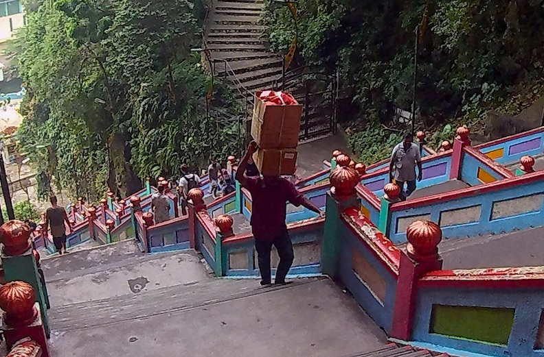 Carrying good on the head climbing up 272 steps to the cave